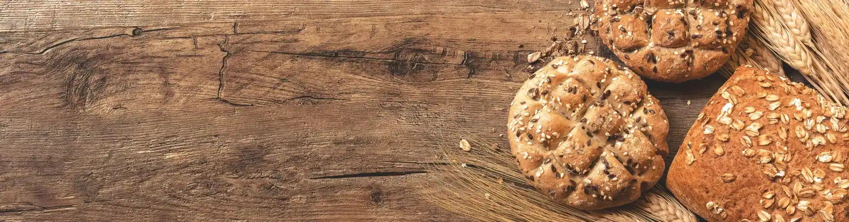 Drei runde Mehrkornbrötchen auf einer hölzernen Unterlage mit Weizenhalmen, gestylt auf einem HOMCOM-Tisch.